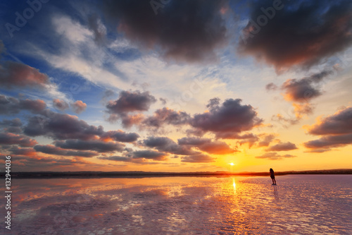 Beautiful sunset, sky with clouds above salt lake. Person take photo of scenic landscape.