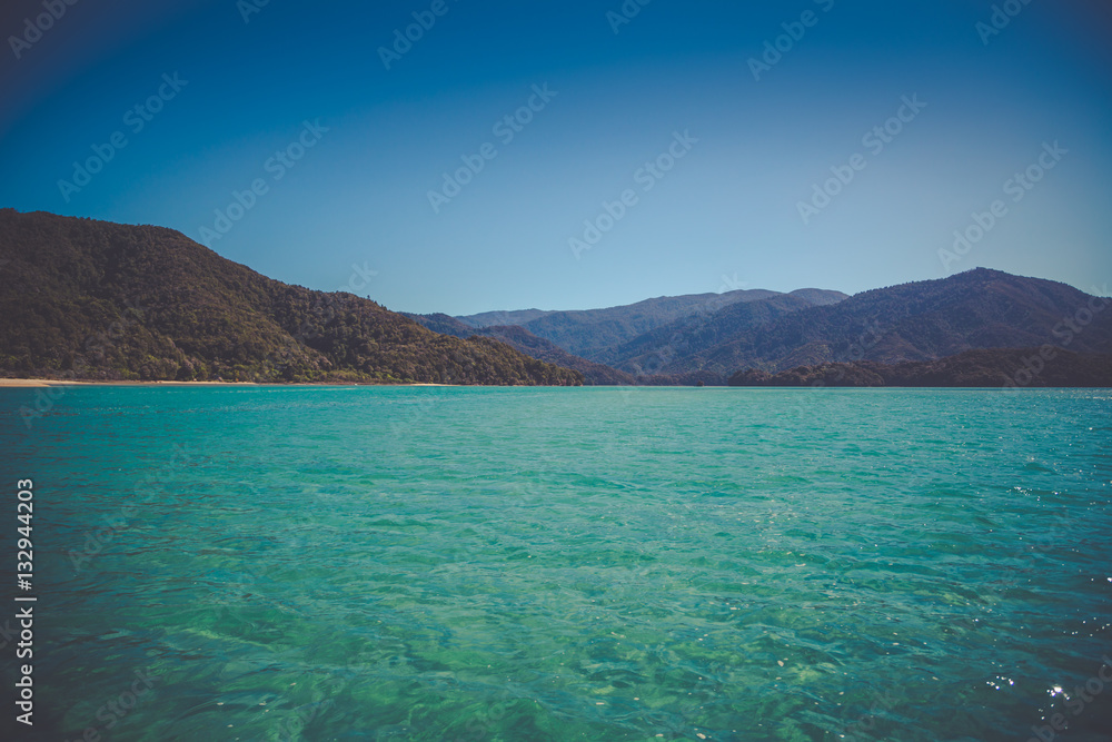Beautiful dreamy ocean landscape with soft green hills of Abel Tasman National Park, New Zealand