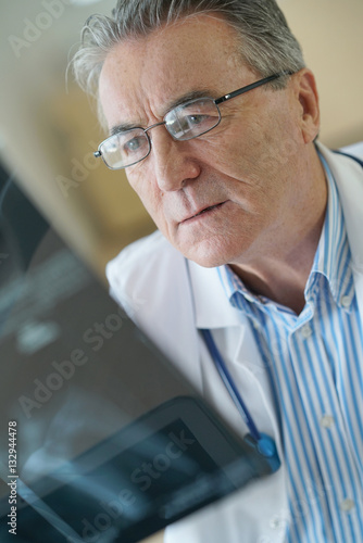 Portrait of senior doctor examining X-ray