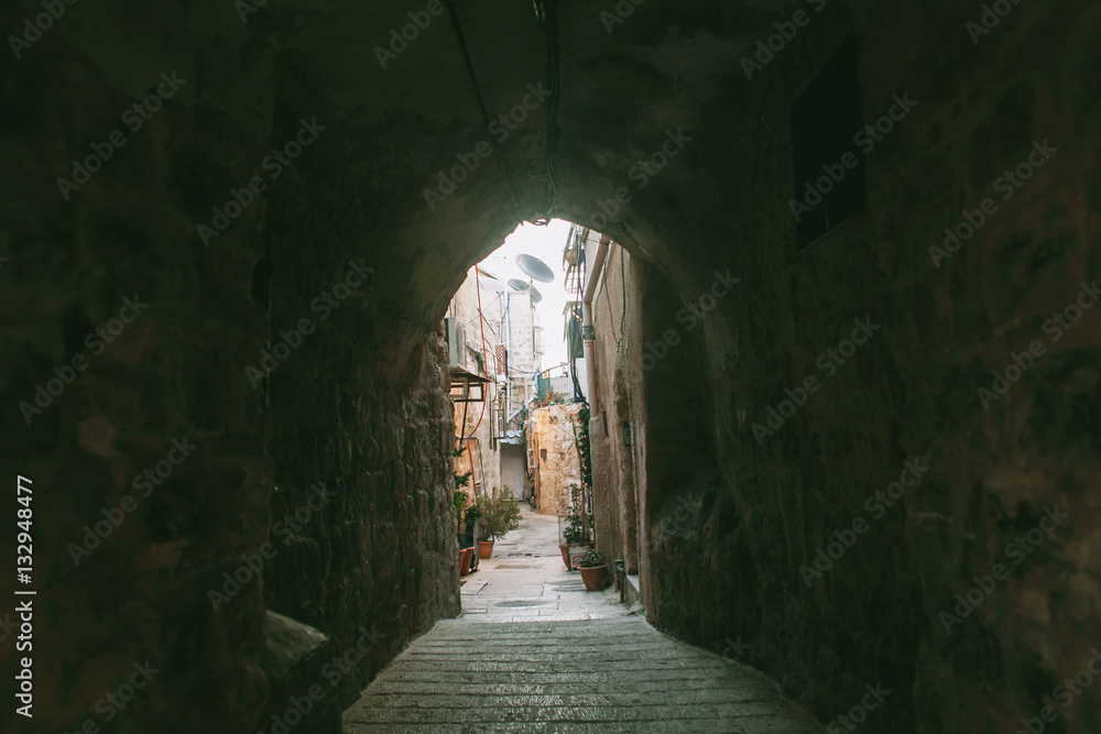Narrow and ancient street of Jerusalem old town and a dark arch