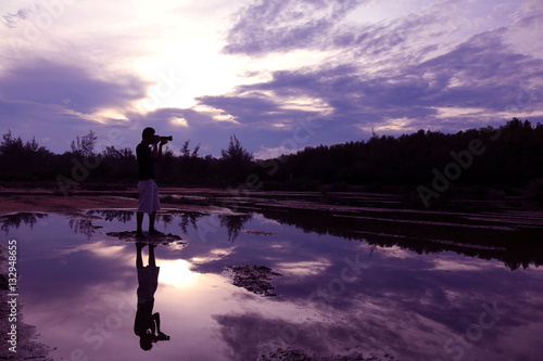 Mirror of purple sky in the morning reflection to the water with shadow of photographer in Thailand.  © THANAGON