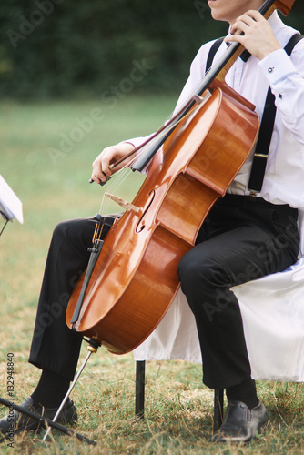 Young man playing cello outside.