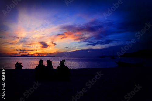 Three girls sitting watching the sunrise at ang thong beach.Thailand. 