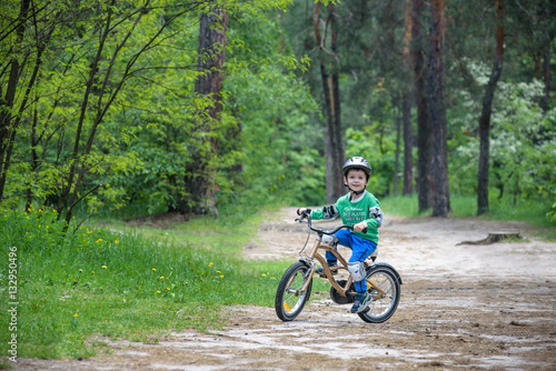 Happy cute blond kid boy having fun his first bike on sunny summer day, outdoors. child making sports. Active leisure for children.