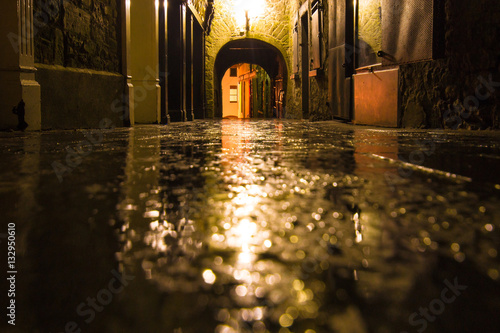 Focus on wet ground along dark medieval alley on a rainy night, Butter Slip, Kilkenny Ireland.