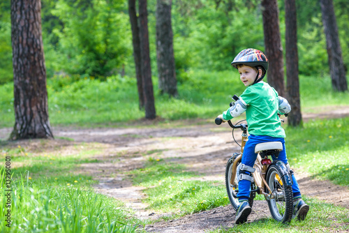 Happy cute blond kid boy having fun his first bike on sunny summer day, outdoors. child making sports. Active leisure for children.