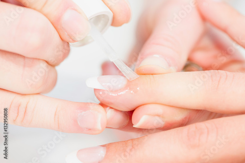 Applying cuticules oil on french manicure nails in beauty salon
