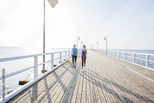 Two women jogging along a jetty