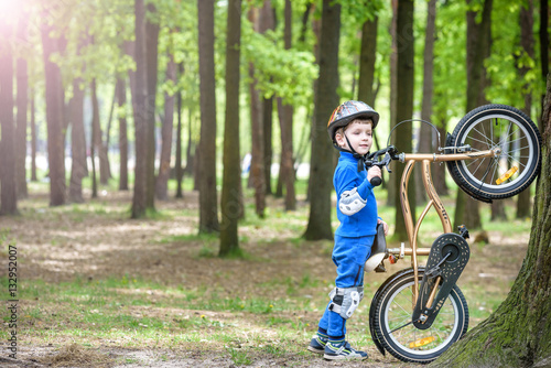 Fototapeta Naklejka Na Ścianę i Meble -  Happy cute blond kid boy having fun his first bike on sunny summer day, outdoors.  child making sports. Active leisure for children.  wear safety helmet.  is smiling and cicling.