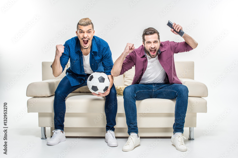 Friends sitting on couch with soccer ball Friends sitting on couch with soccer ball