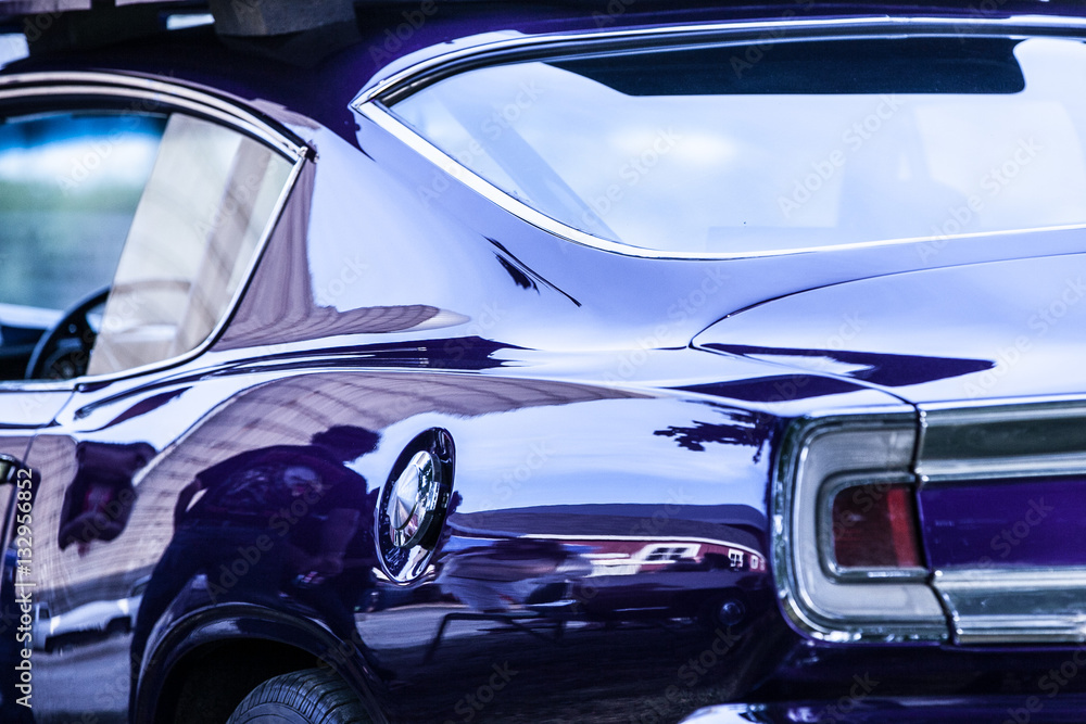 A shiny purple car show car reflecting a barn.