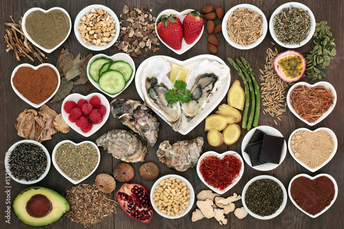 Large aphrodisiac health  food collection for good sexual health with foods in porcelain bowls and loose on dark oak wood background. Used to stimulate sexual drive.Top view