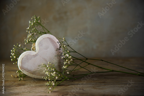 Heart from wood and white flowers against a rustic vintage background
