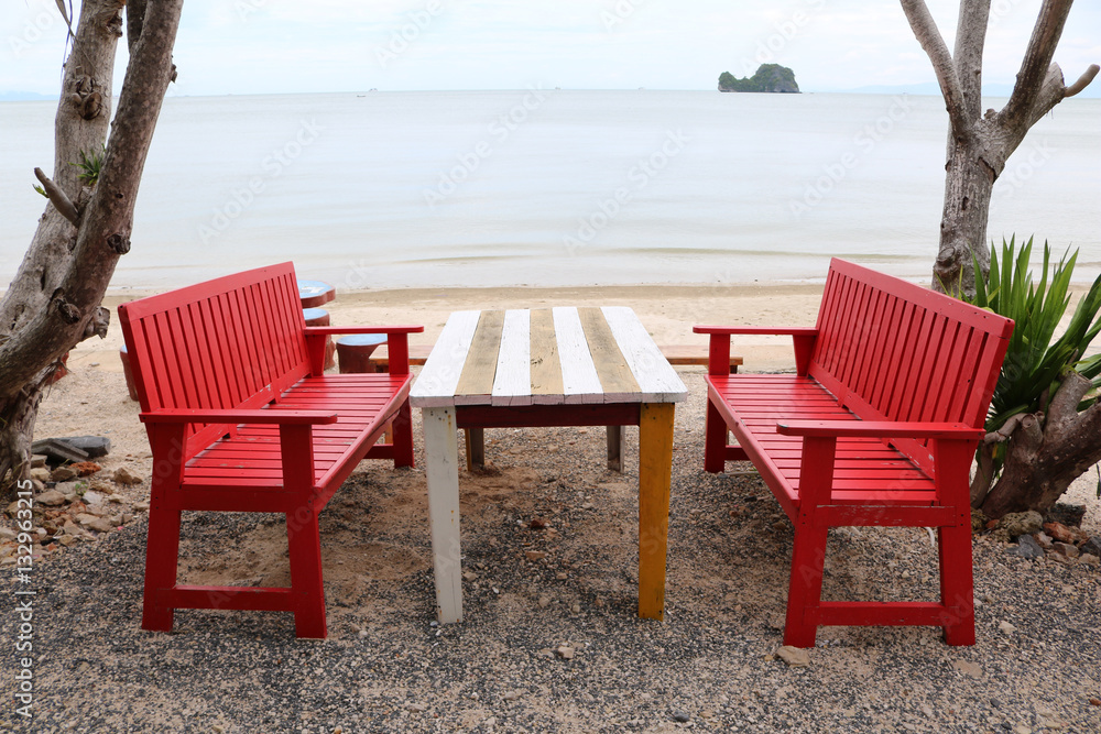Red wooden table and chairs on the beach. 