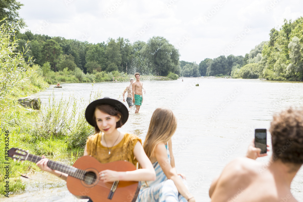Group of friends relaxing on the riverbank Group of friends relaxing on the riverbank
