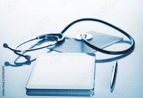 Tablet computer with stethoscope and pen on the table