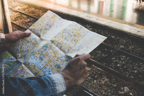 Young traveler holding travel map outside train window on a platform in the train station. Concept travel by train.