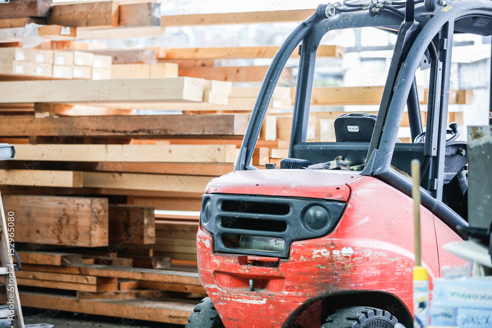 Roter Gabelstapler vor einem Holzstapel Roter Gabelstapler vor einem Holzstapel