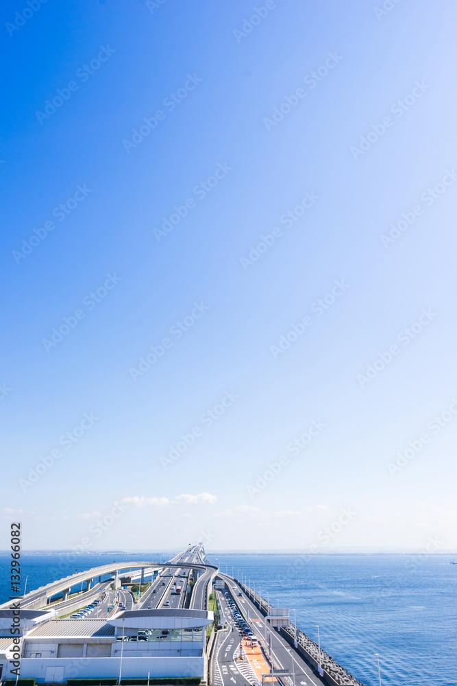 Fototapeta premium panoramic bird eye top aerial view with beautiful sea level with highway road under dramatic clear glow and fantasy blue sky in Umi Hotaru parking area island Tokyo bay aqua line, Japan