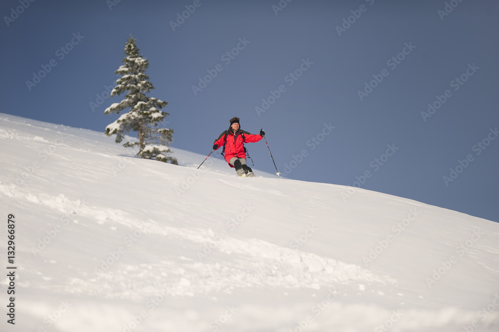 Mid adult man skiing down steep hill in beautiful nature. Behind him is spruce tree.