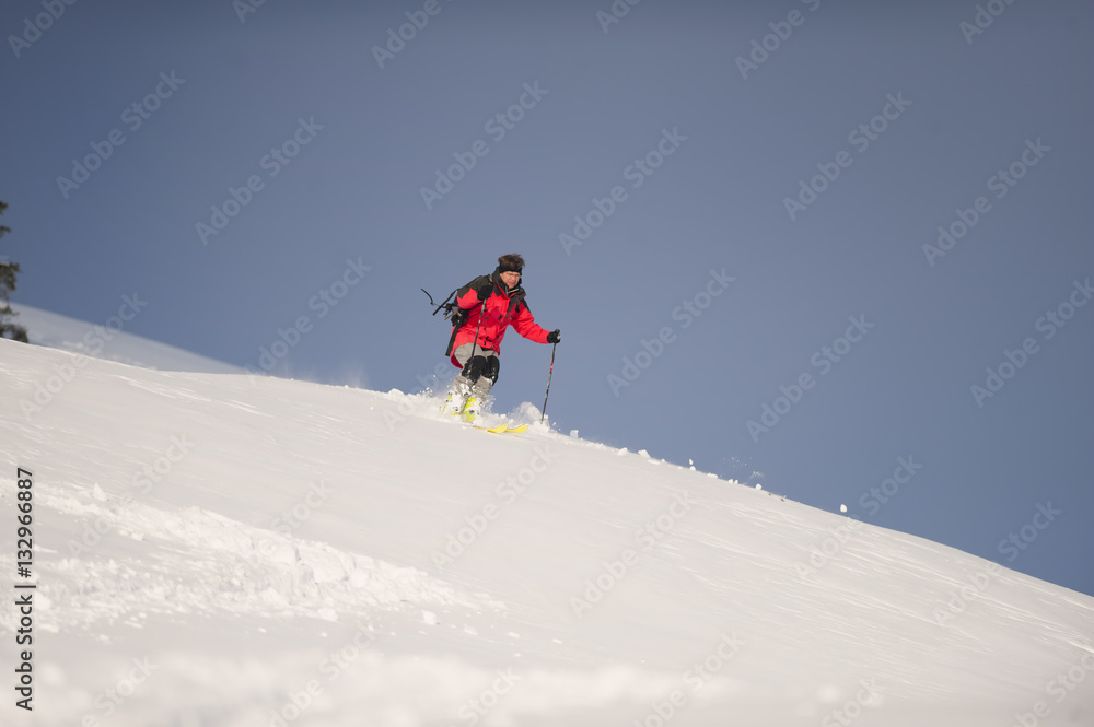 Mid adult man skiing down steep hill in nature on winter time.
