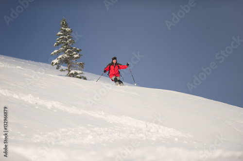 Mid adult man skiing down steep hill in beautiful nature. Behind him is spruce tree.