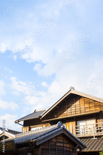 culture concept - japanese traditional historical wooden old house under golden sun and morning blue cloudy sky