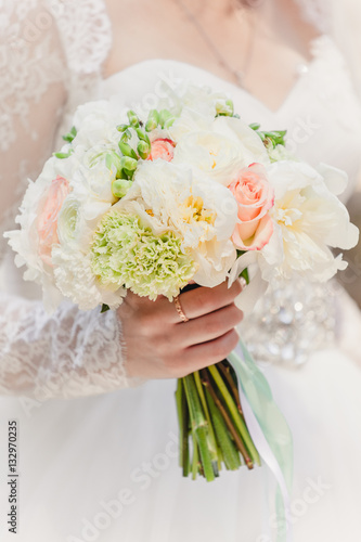 bride with a wedding bouquet of roses and peonies