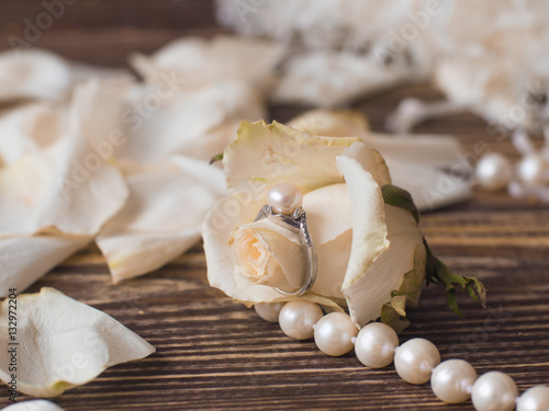 pearl necklace and ring with white flowers on woden background, macro