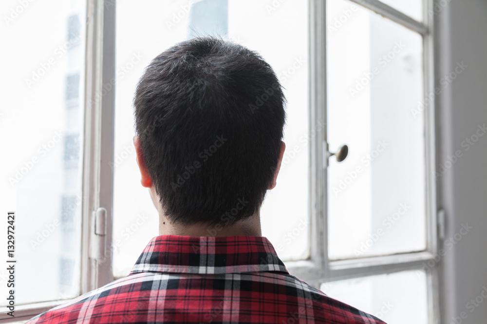 Young man looking through the window Young man looking through the window