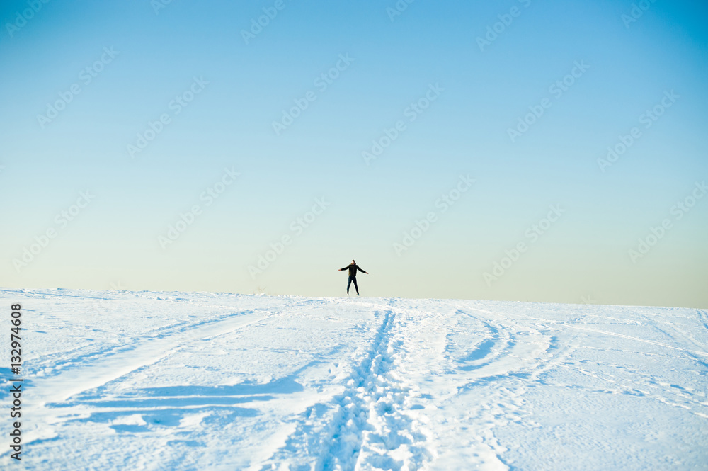 man in warm clothes with a beard is walking on the street in the winter in a warm sunny day at the river against the sky, jumping up and running in the snow