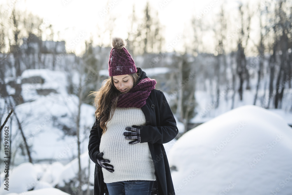 Fototapeta premium Young happy pregnant woman in snowy forest
