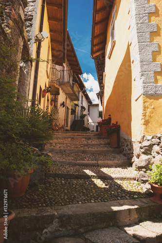 Narrow town street at daytime. Green plants and stone stairs. Explore old district of Stresa.