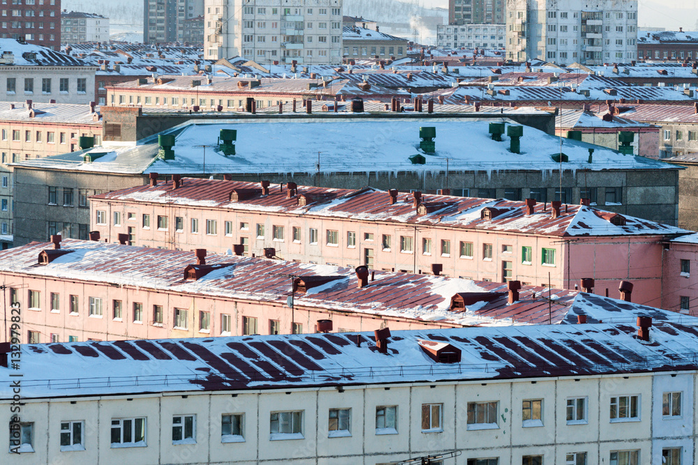Snow-covered roofs of multi-storey town houses.