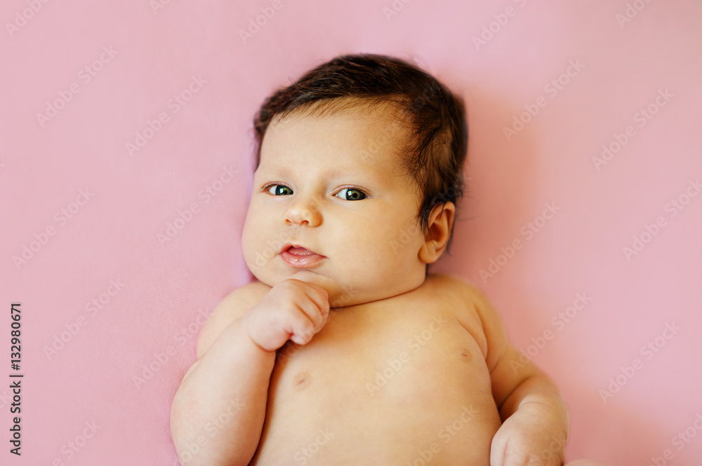 Portrait of a cute 4 months old baby lying down on bed, top view Stock