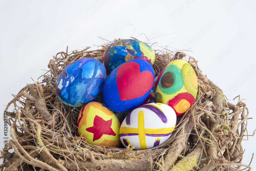 Obraz premium Detail of painted Easter eggs placed in a nest with different forms and animals in white isolated background.