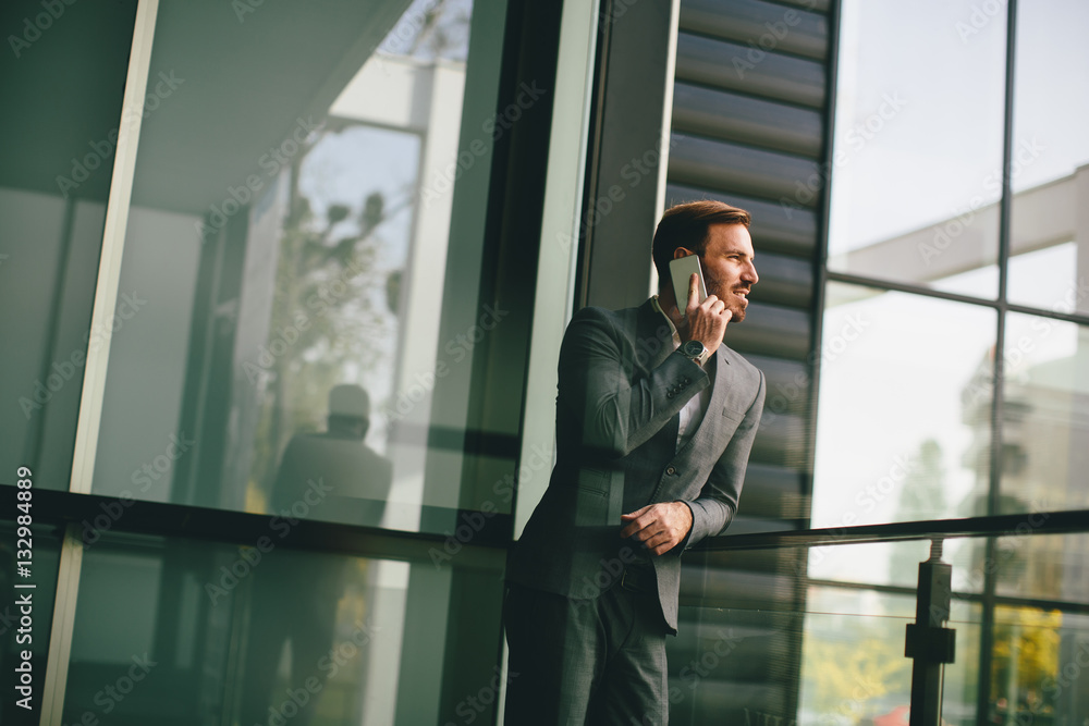 Young man with mobile phone by office building Young man with mobile phone by office building