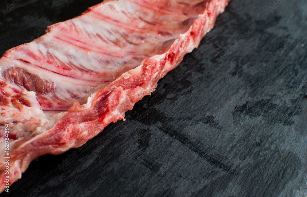 Raw pork ribs on black stone background