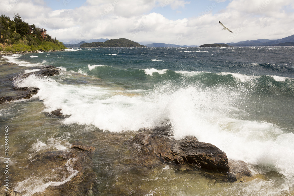 Lake in Bariloche, waves, fowl flying blue sky with clouds.
