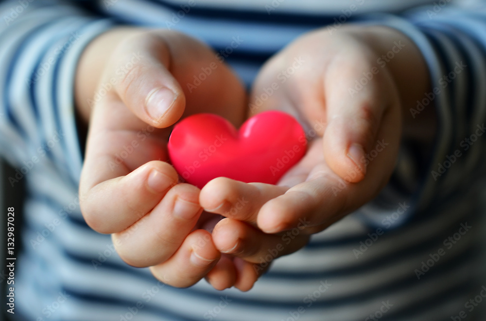  child holding a small pink heart. symbol of love, family, hope. Backgrounds for cards on Valentine's Day. Backgrounds for social posters about the preservation of the family and children.
