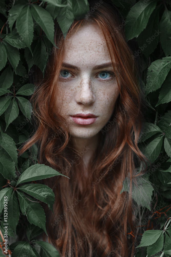 Beautiful girl with red hair in green leaves Stock Photo | Adobe Stock