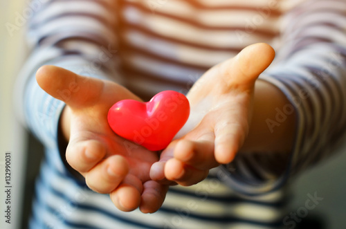 child holding a small pink heart. symbol of love, family, hope. Backgrounds for cards on Valentine's Day. Backgrounds for social posters about the preservation of the family and children. photo