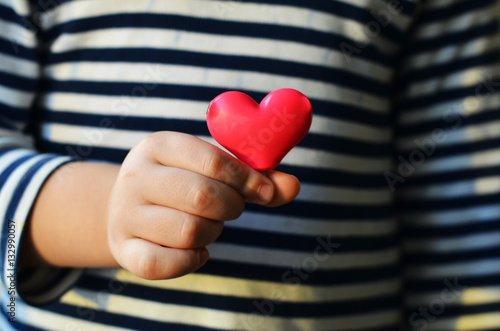 child holding a small pink heart. symbol of love, family, hope. Backgrounds for cards on Valentine's Day. Backgrounds for social posters about the preservation of the family and children.