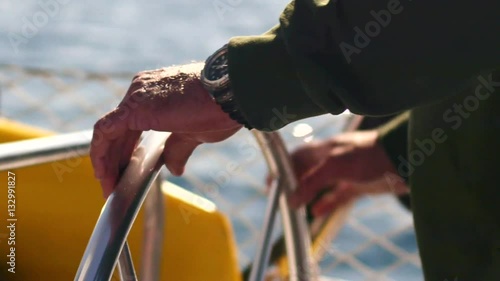 Male hand on a rudder, helm on a sailboat sailing in the sun in a certain direction. photo