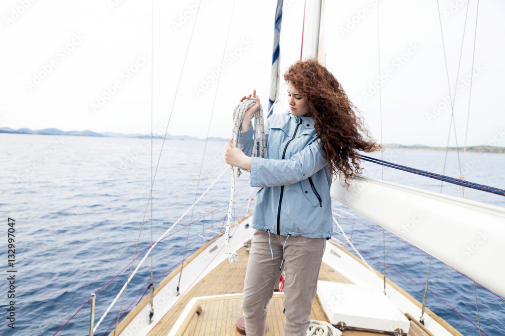 Young woman on yacht curling up rope Young woman on yacht curling up rope