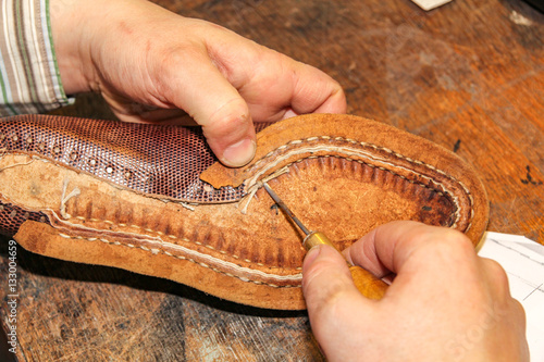 Repairing a brown leather shoe shows the craftsmanship of a Dutch shoemaker in Oegstgeest. photo
