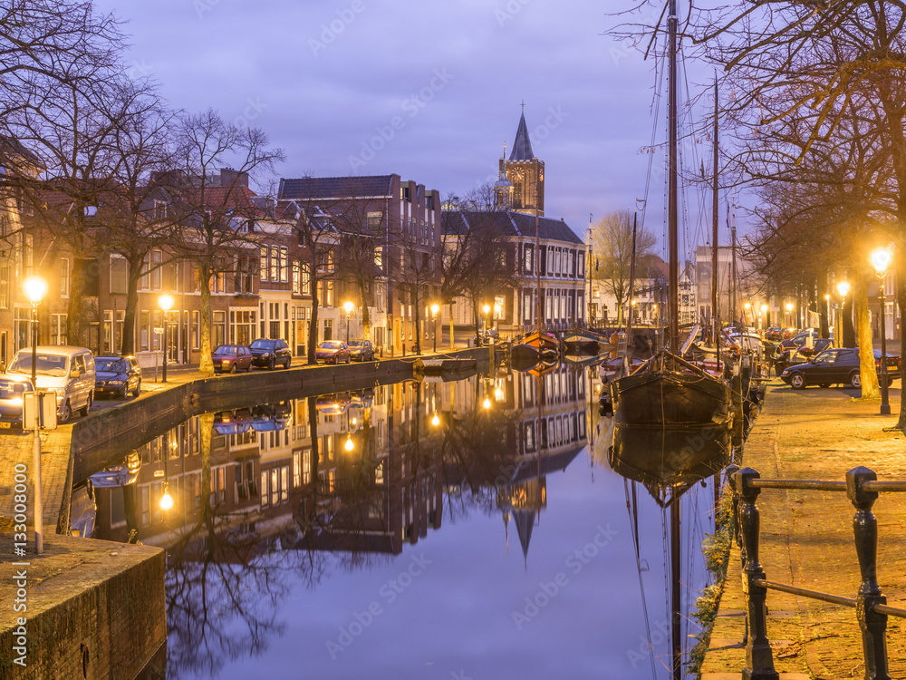 Dutch old city Schiedam landscape during calm weather with reflections in a canal, old barges and a church