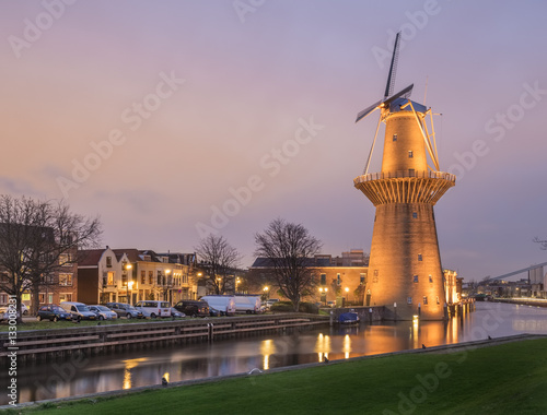 Dutch old city Schiedam landscape during calm weather with reflections in a canal and old windmill photo