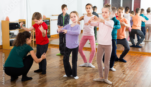 attentive boys and girls rehearsing ballet dance in studio