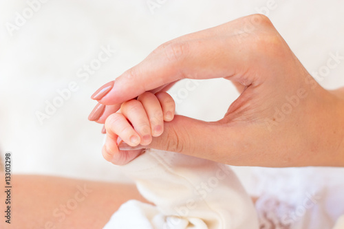 Close-up of legs, handles child. Happy mother kissing the feet, hands, fingers, the nose of the child. Gentle photo mom and baby. © Kristina89